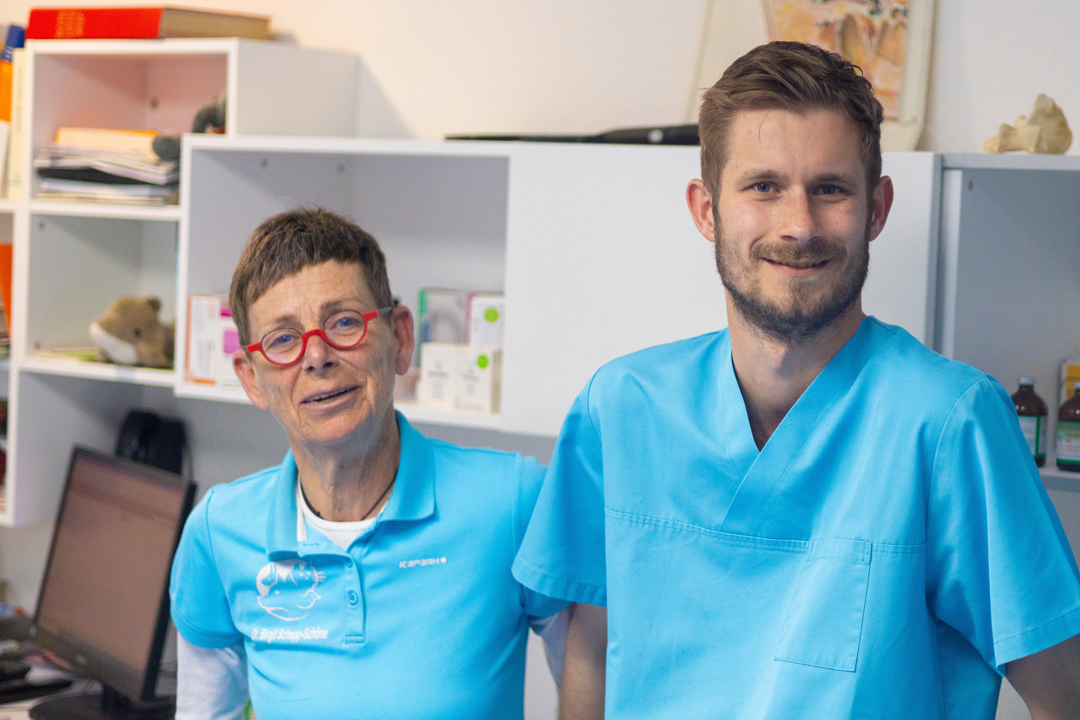 Zwei Tierärzte in blauen T-Shirts und OP-Kleidung in einer Tierarztpraxis.
